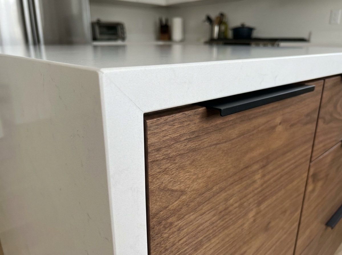 Mitered quartz waterfall meeting walnut cabinetry